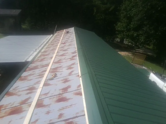 Old rusted panels beside newly installed green metal roofing — Wind Damage Roof Repair by Roofing Brothers in Saline