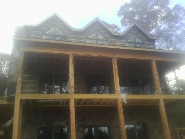 Dormers and porch framing on a large log home under construction — Roof Coating work by our crew in Saline