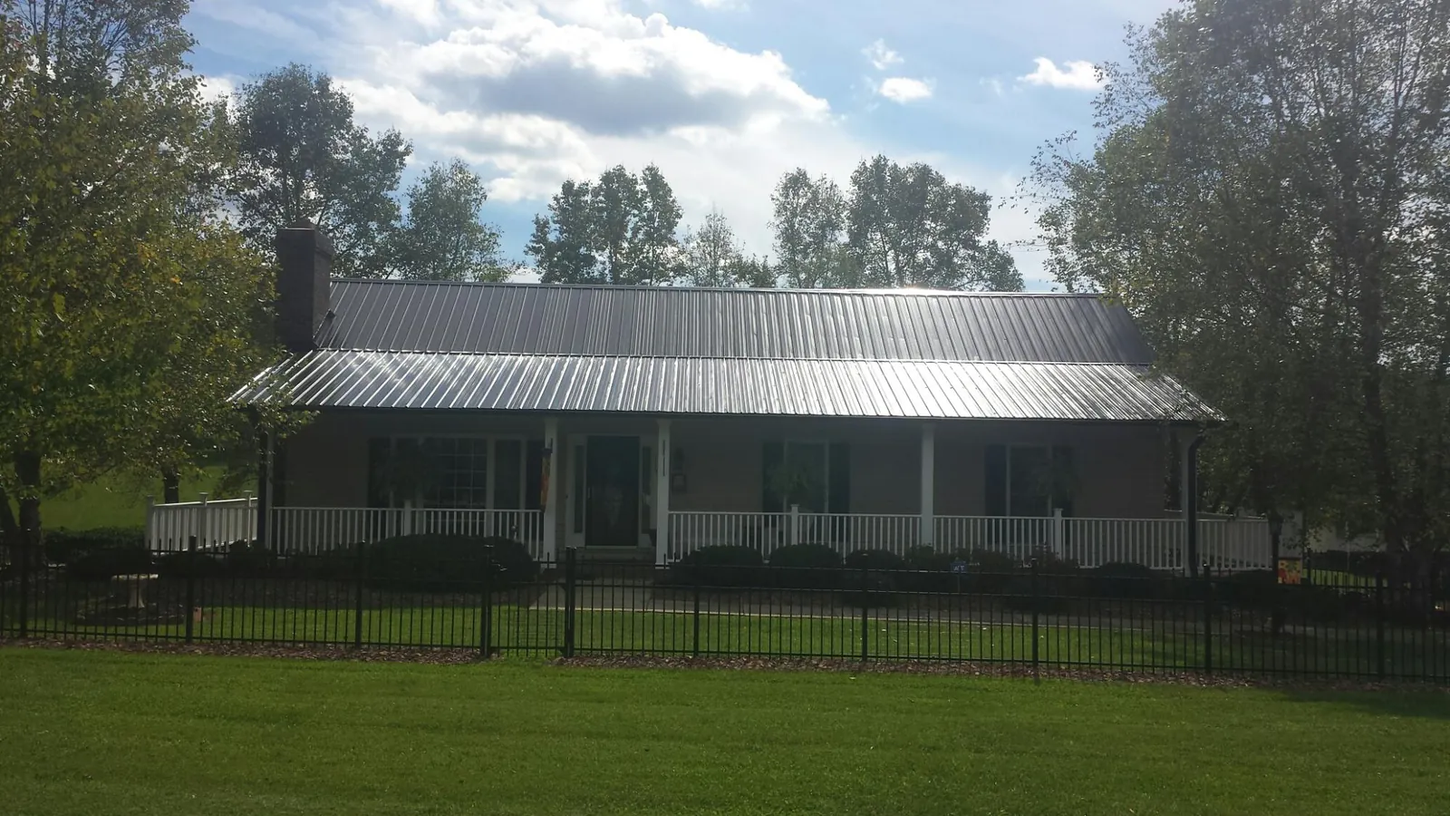 Gray metal roof on a brick ranch with a full width front porch — Gutter Guard Installation work by our crew in Saline