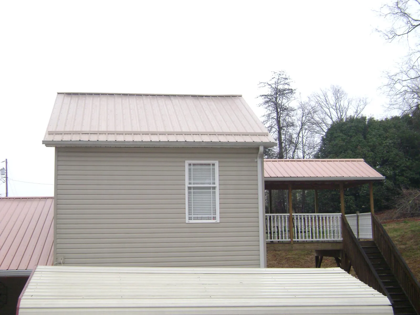 Tan metal roofs on a two story addition and attached porch, from a Roof Replacement job in Saline